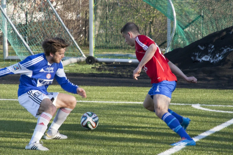 two soccer players in red and blue are playing on the field