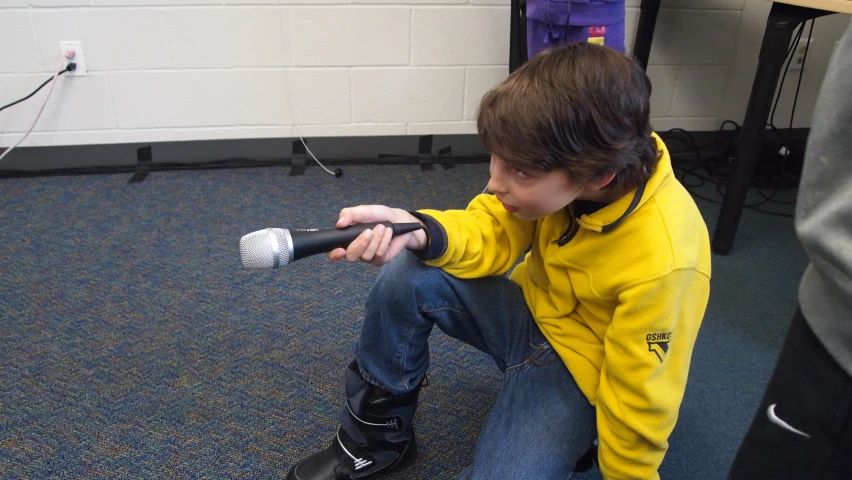 a young man is sitting and holding his remote controller