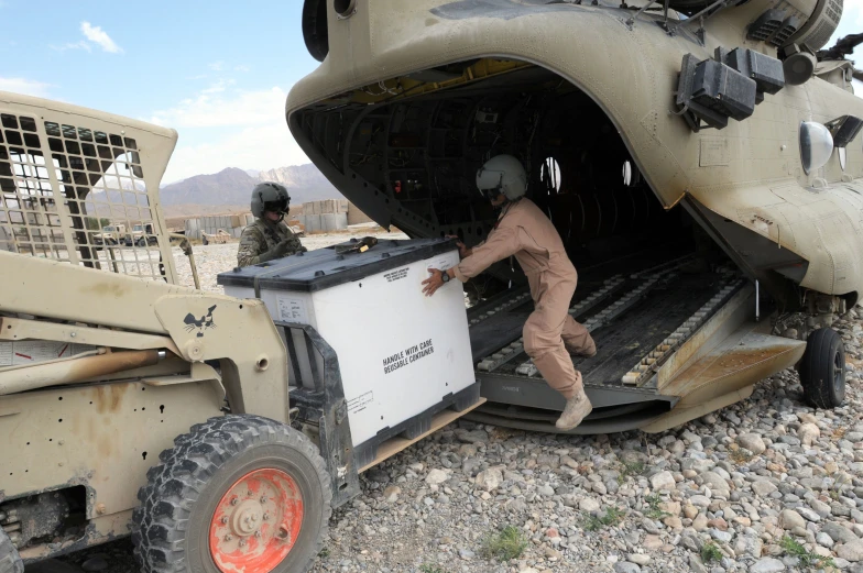 two soldiers work on a large vehicle that is equipped with equipment