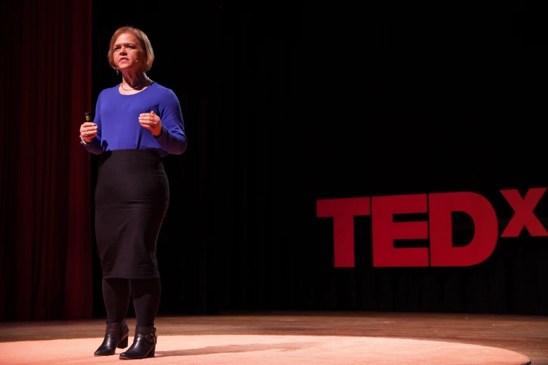 a woman is standing on a stage holding up her hands