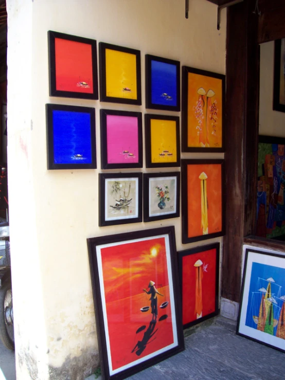 framed art pieces on a wall next to a bike