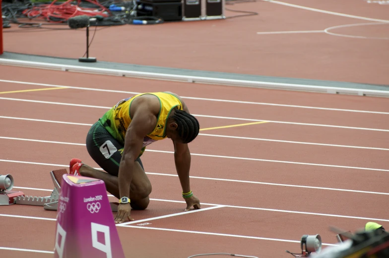 an athlete looking down at the ground while preparing to start his race