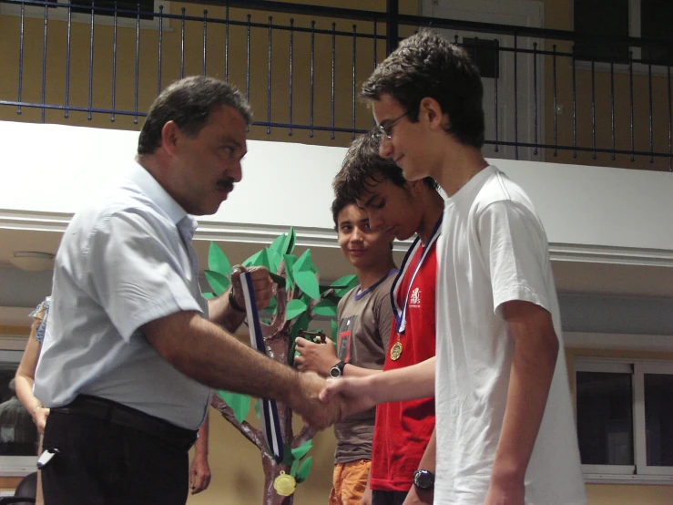 three s in white shirts shaking hands with a man