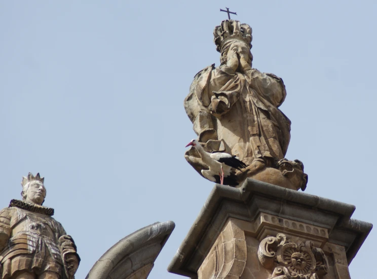 two statues, one of which is standing up and holding a cross