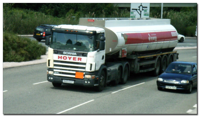 a small car is driving next to a large tanker truck