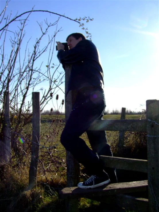 man leaning on a wooden fence looking back