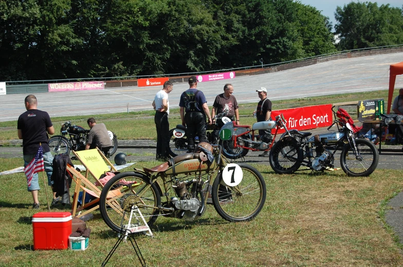 motorcycles sitting on grass with people standing behind them