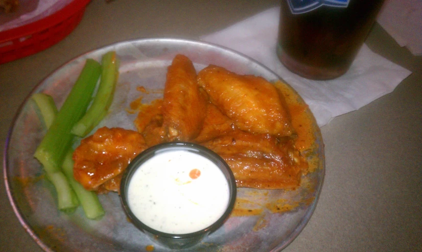 a plate topped with wings and a cup of beer