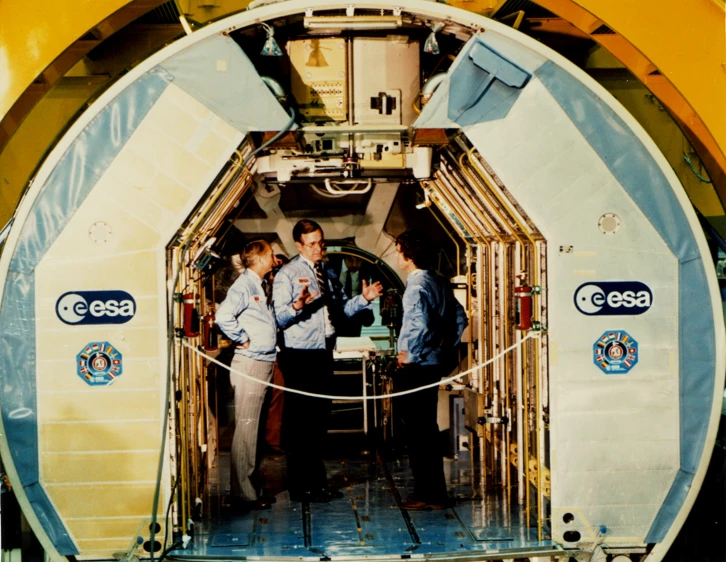 three men are standing in the doorway of a space station
