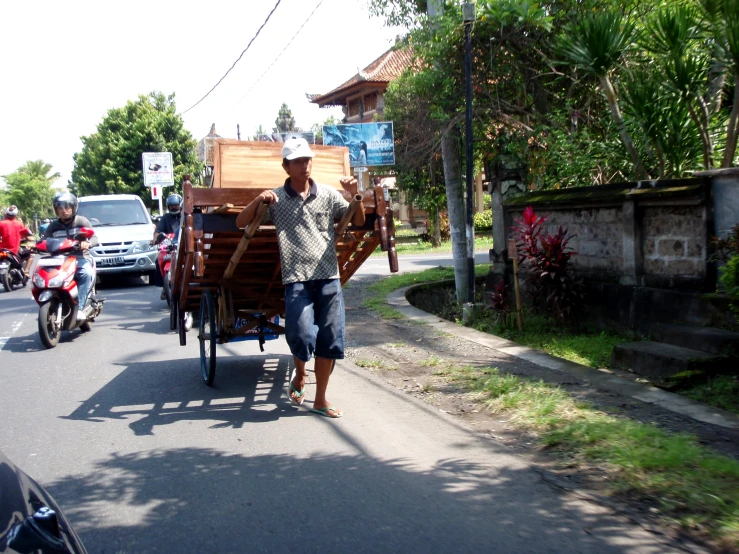 a man hing a wagon behind him on the street