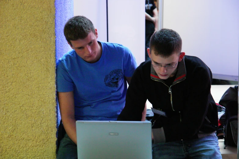 two men sitting down, looking at a laptop screen