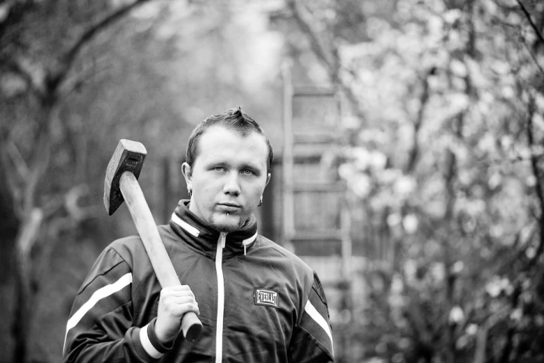 the young man is holding an ax, outside