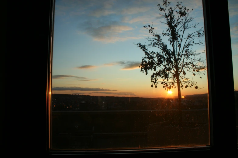 a window view of the sun setting over trees