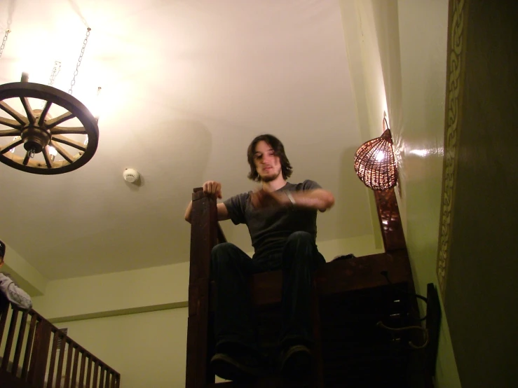 man sitting on bunk bed next to a ceiling fan