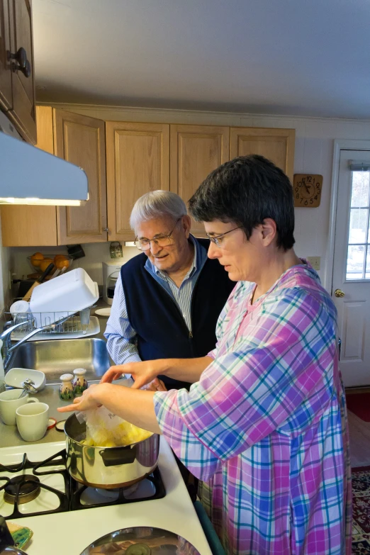 two older people in the kitchen preparing food together
