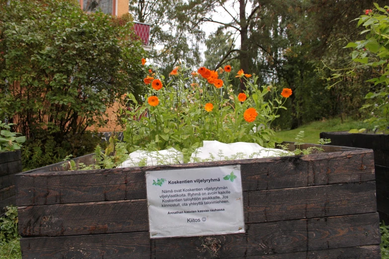 a sign describing a garden has been placed on a wooden planter box