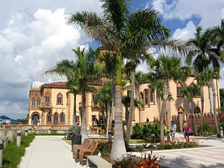 palm trees line the sidewalk leading to an upscale mansion