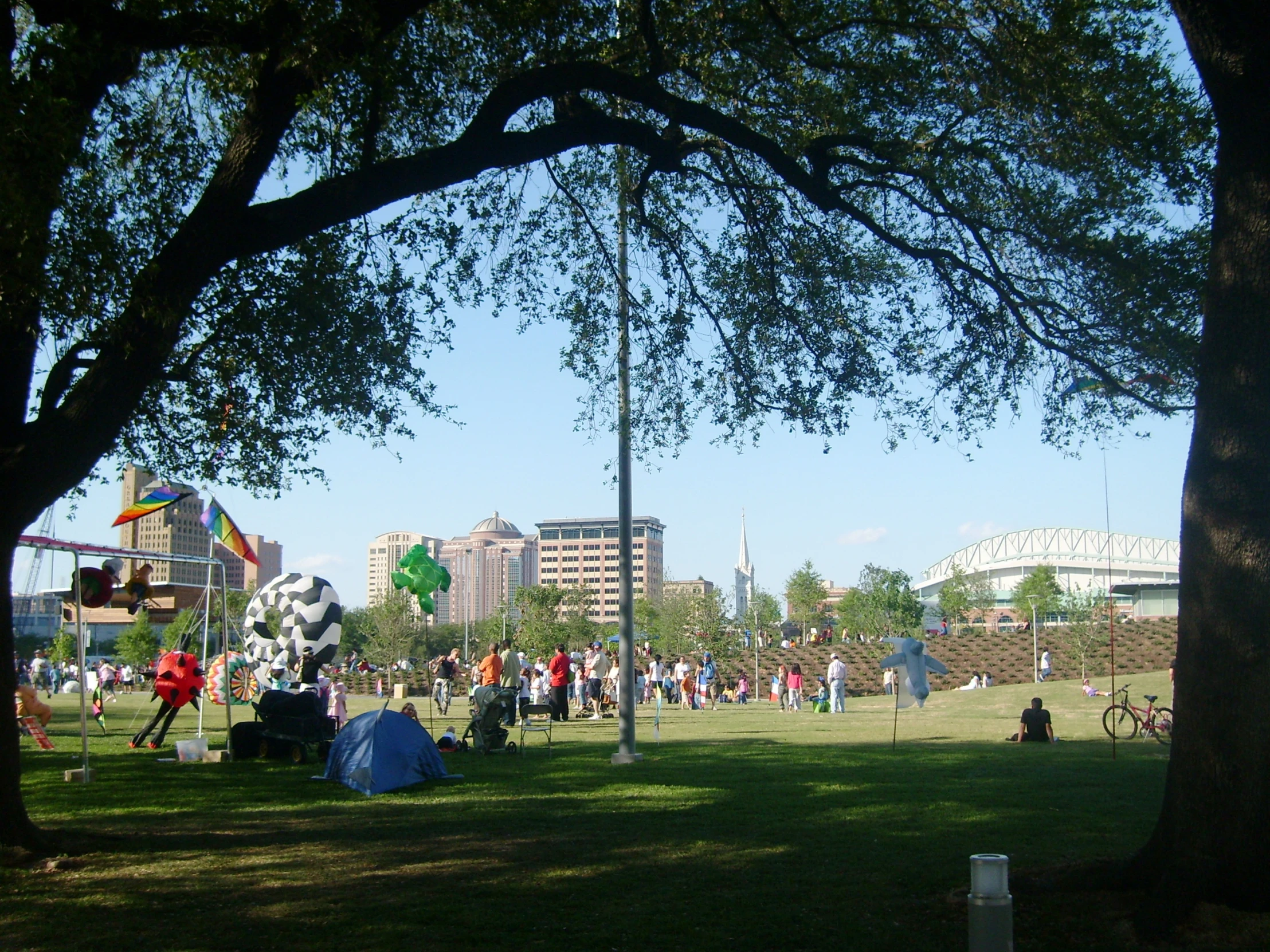 an open park with many people and tents in the background