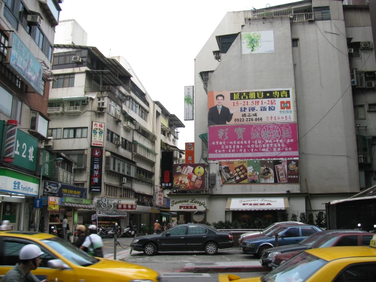 an intersection with cars, taxis and pedestrians passing by