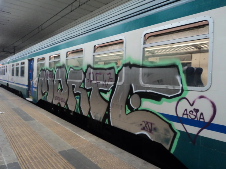 a train with colorful graffiti next to a platform