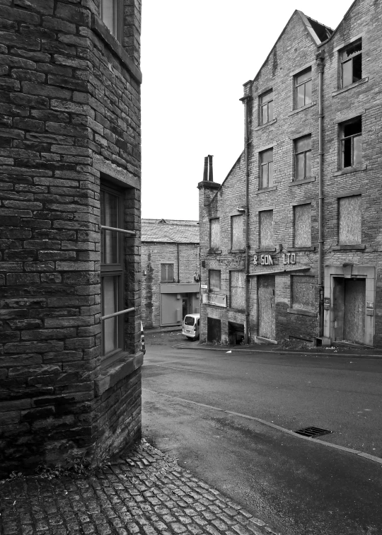 an old empty street with buildings and a car on the road