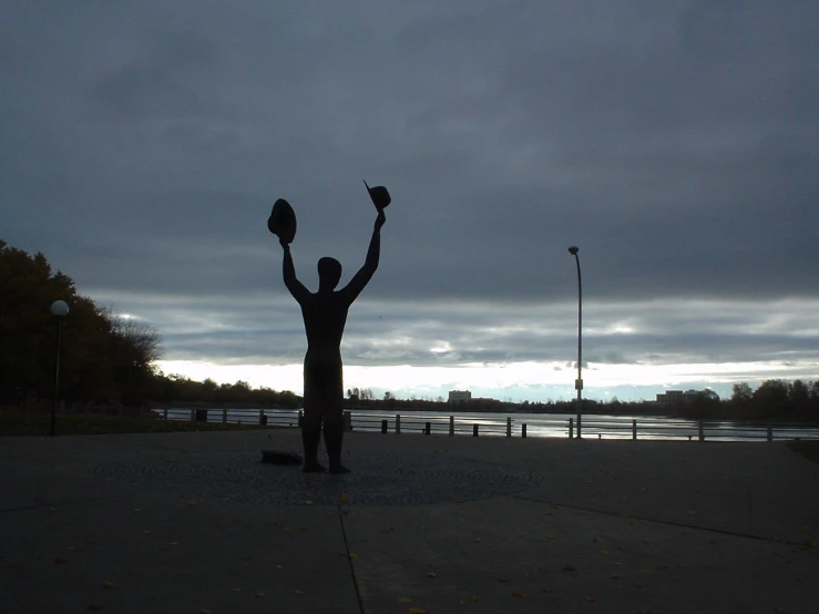 the silhouette of a person with a pair of scissors stands in front of a lake