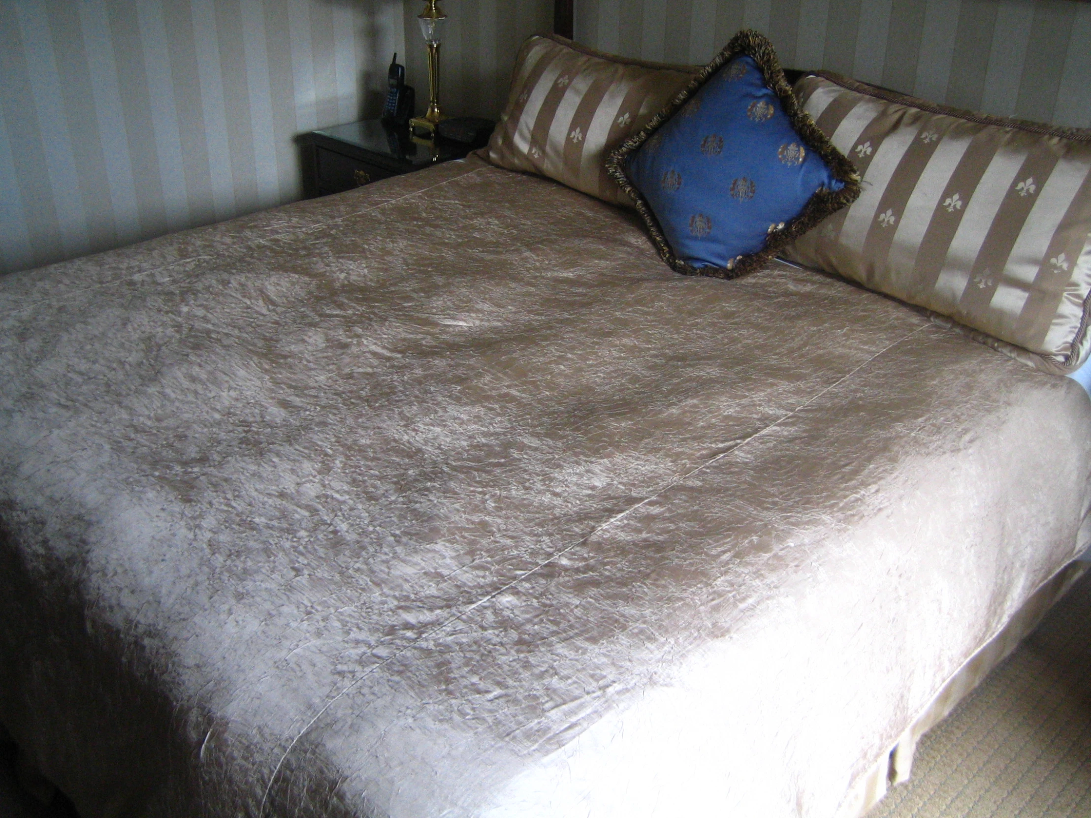 a well made bed with white bedspread and striped wall