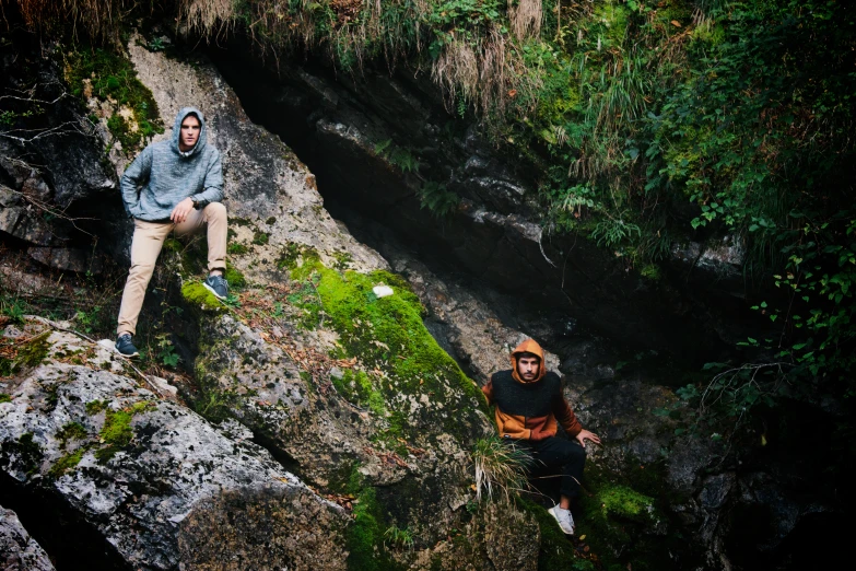 two young men sit on rocks and look down