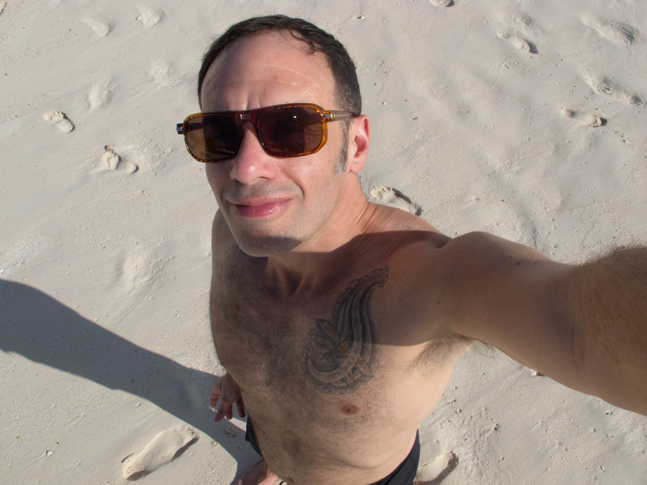 a man with sunglasses on the beach posing for a po