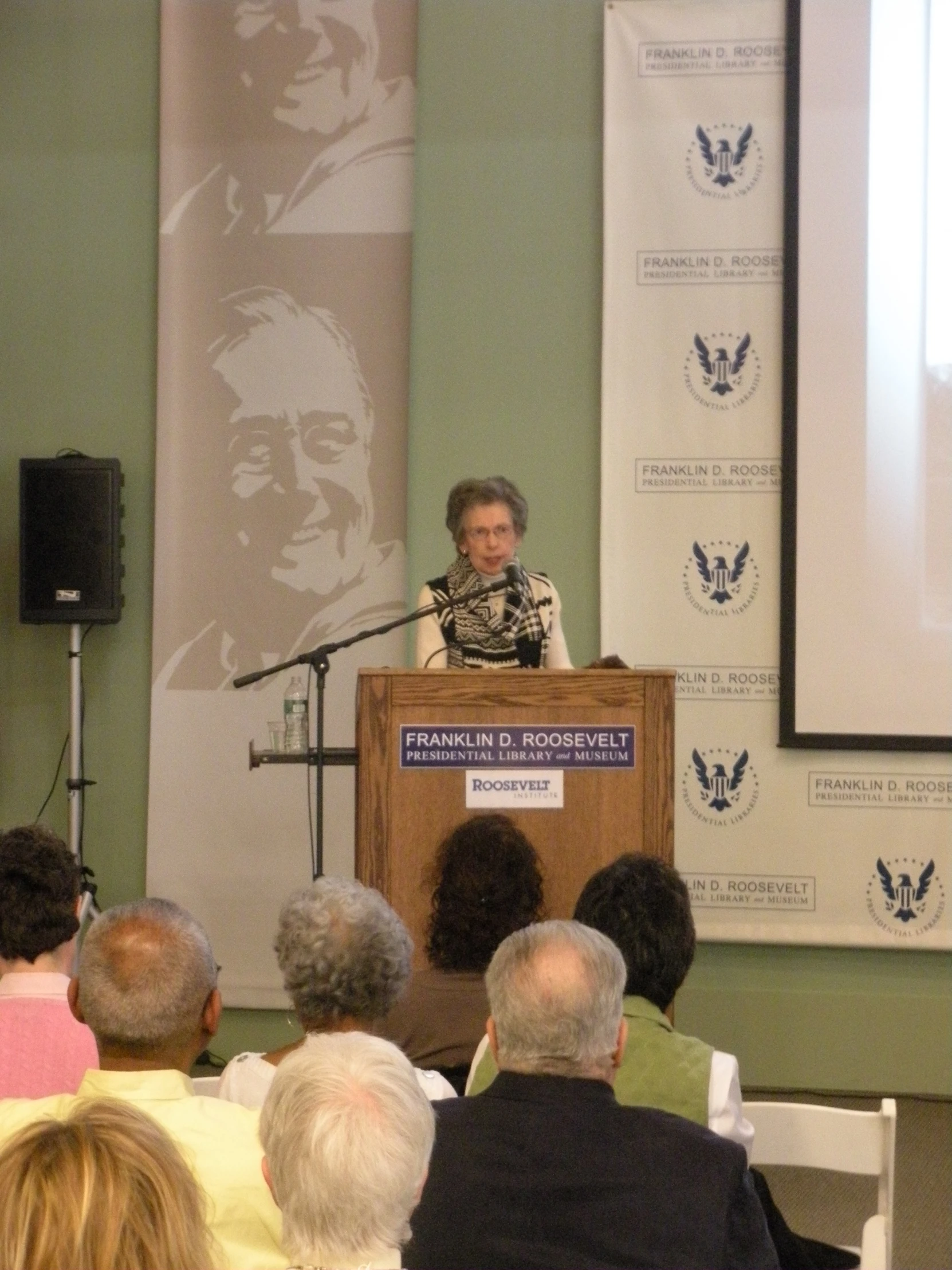 an elderly woman standing in front of a lectern