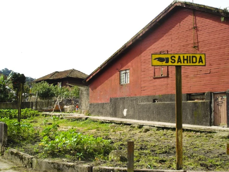 a red building with a wooden fence near green bushes