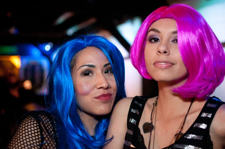 two women that are sitting down together wearing bright blue hair