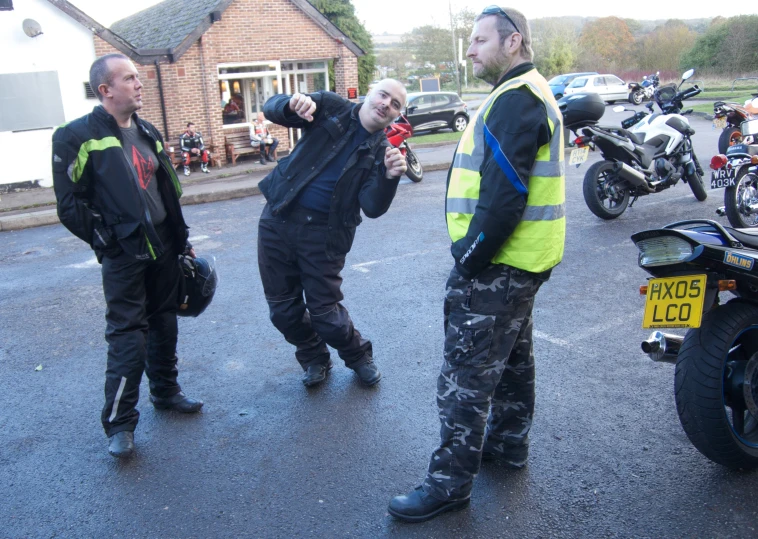 three men standing together in the middle of a road