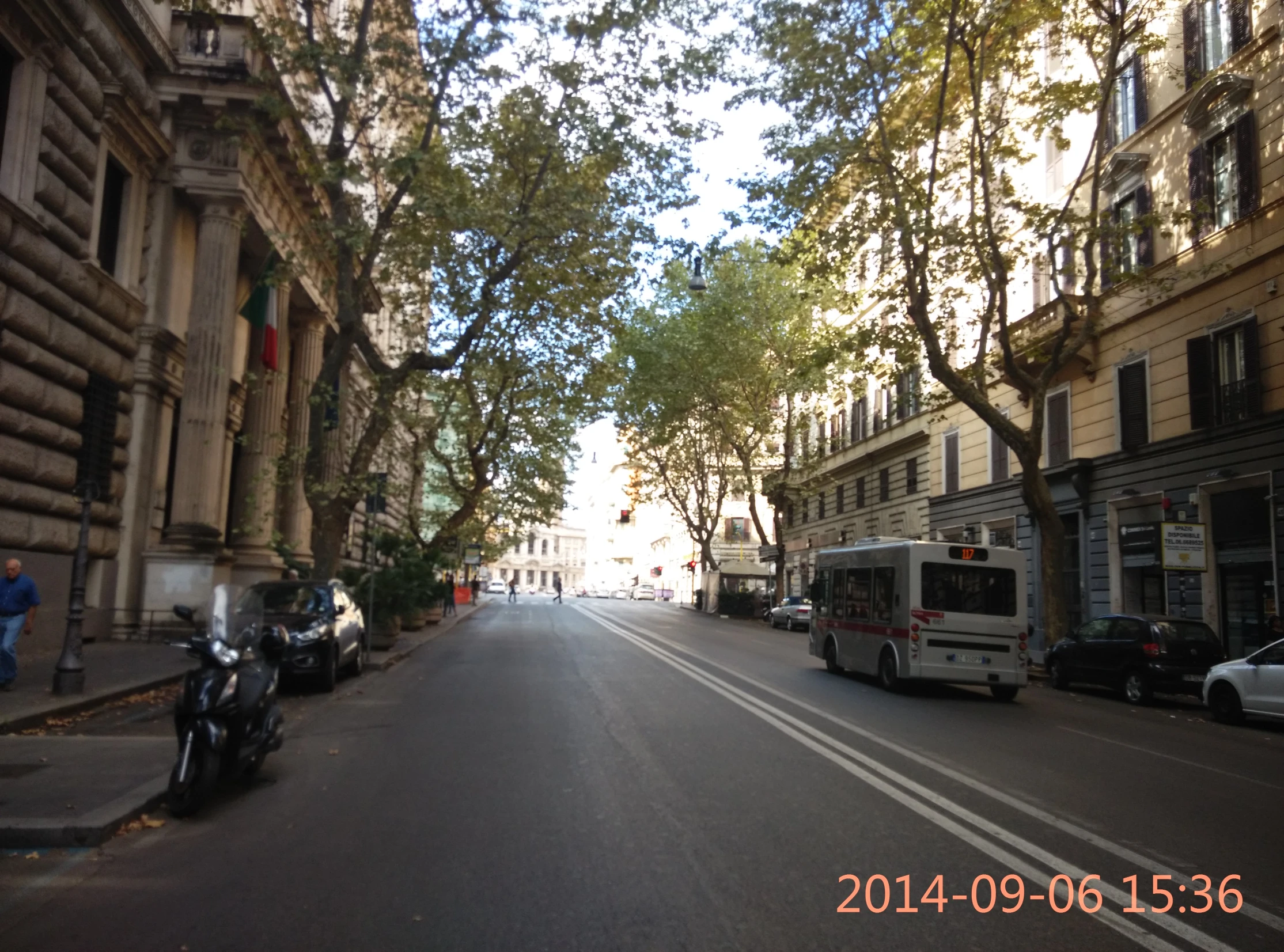 a narrow city street lined with parked motorcycles