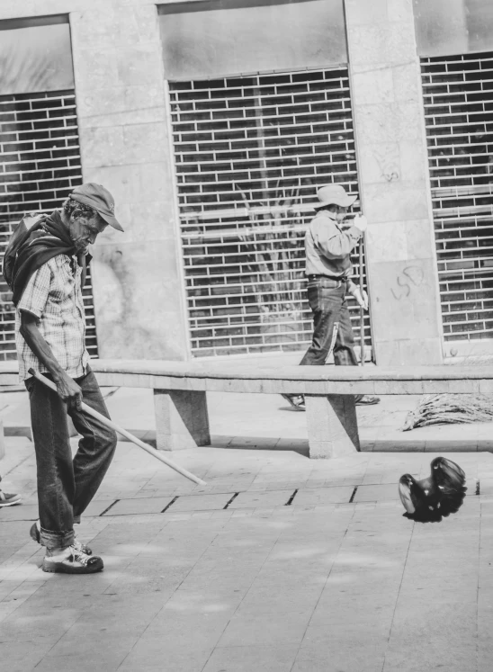 a man walking on the sidewalk near another person with a bat