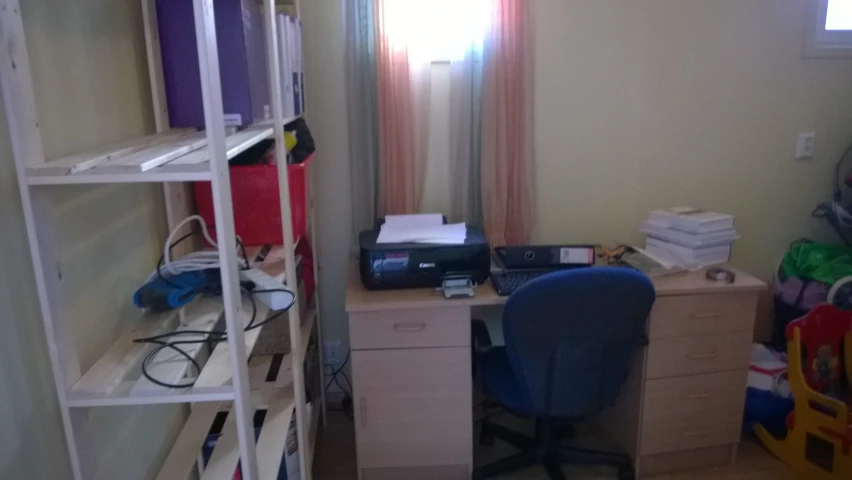 a cluttered room with a desk, bookshelf, and computer