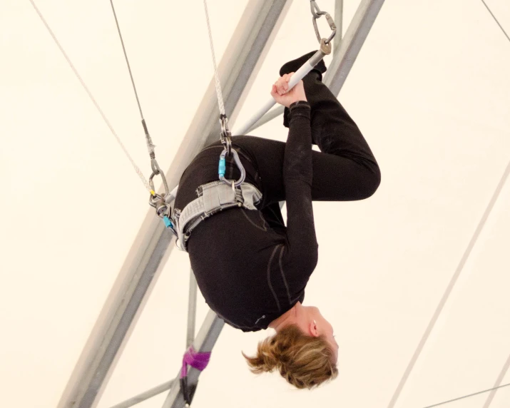 woman on aerial swing suspended upside down with hands