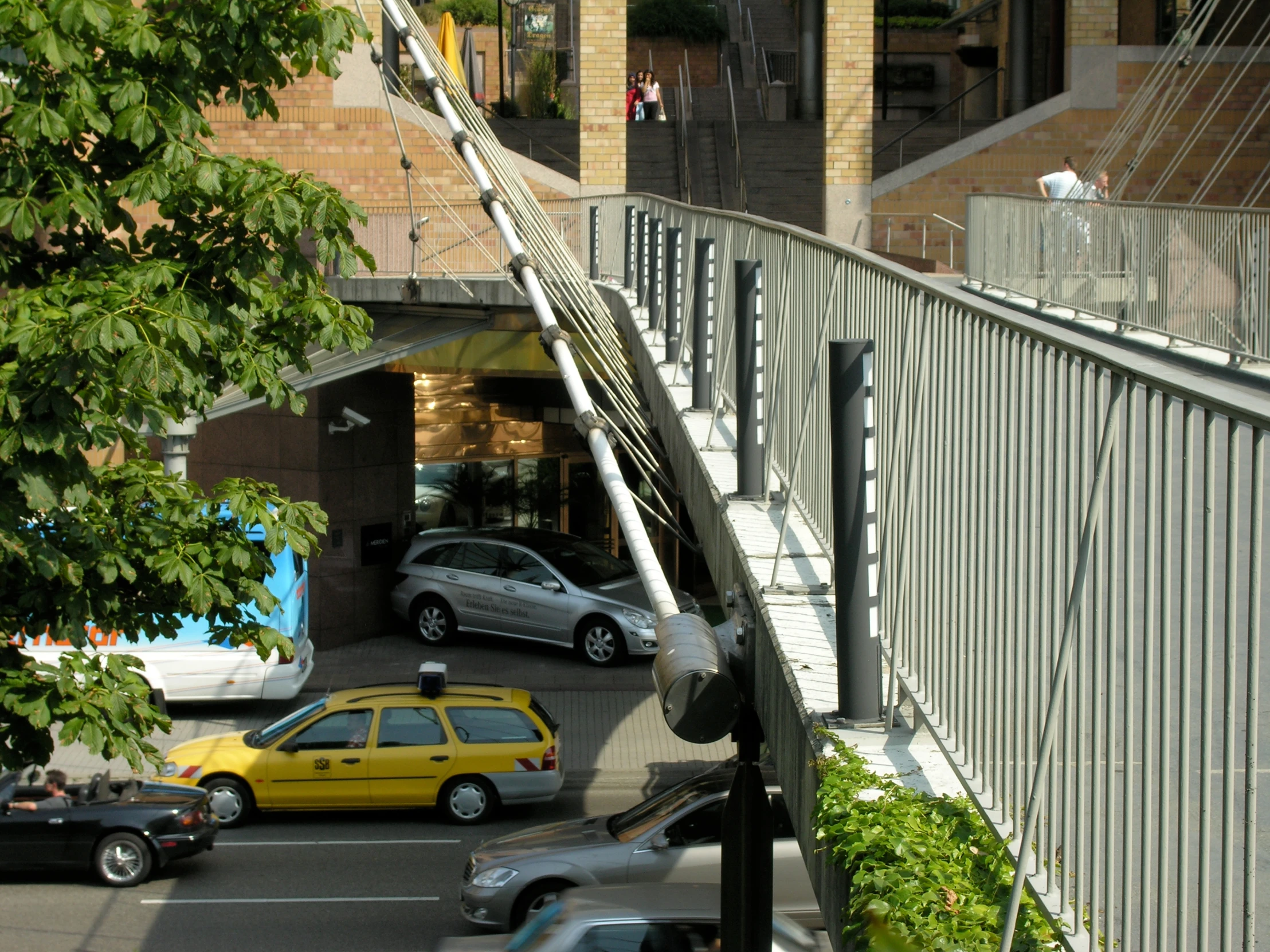 cars driving down a hill near a building and an overpass