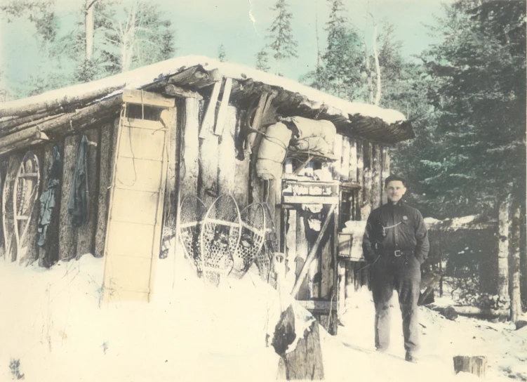 an old picture of an old woman outside of a cabin