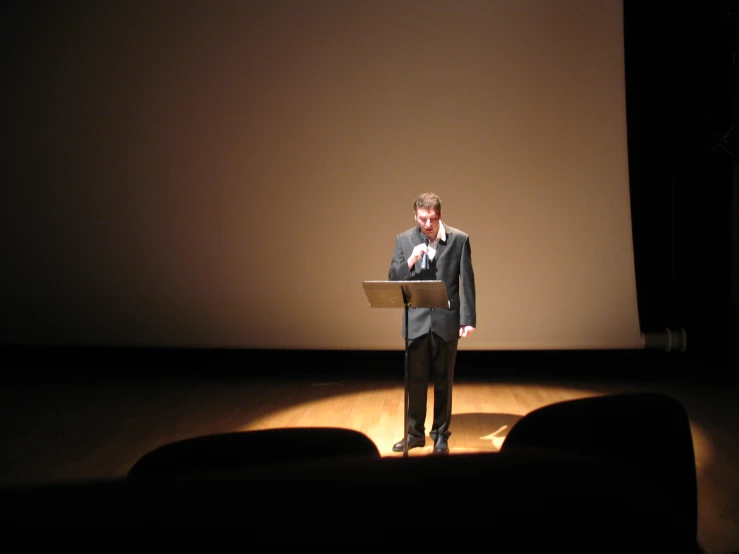 a man standing on stage with a laptop