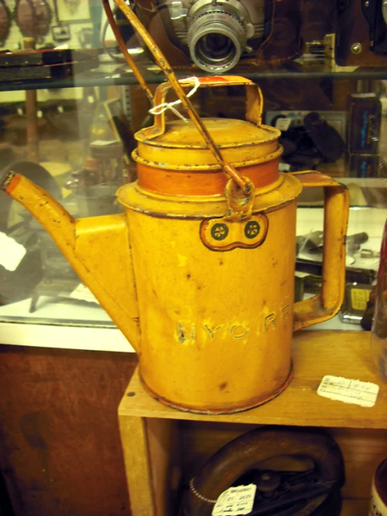 old yellow painted metal watering pot on display