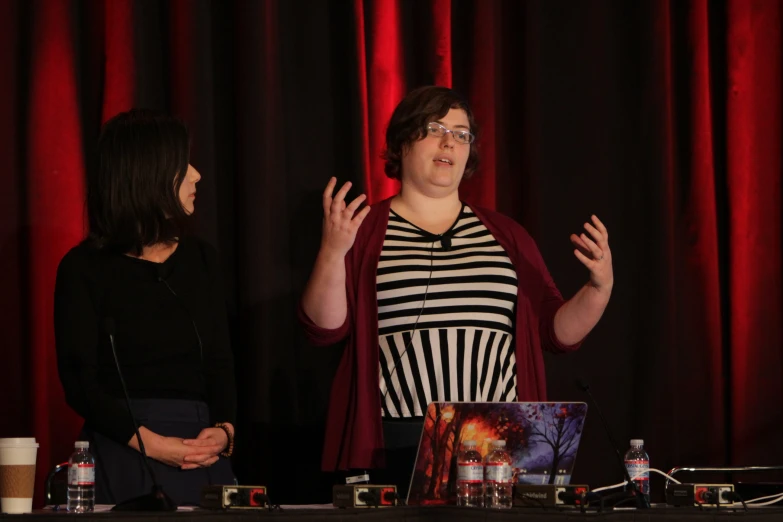 two women speaking at a table with microphones