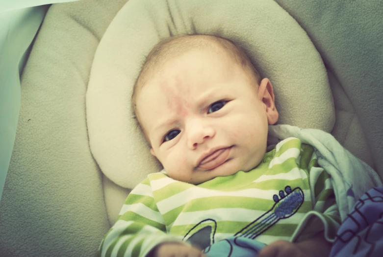 a baby in a seat holding onto its hand