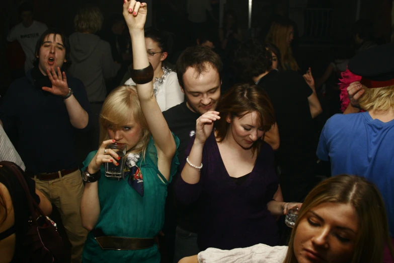 people dancing at a party with their arms in the air