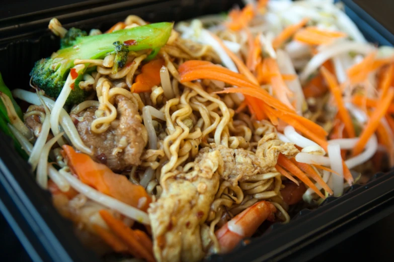 this container is full of noodles, vegetables and meat