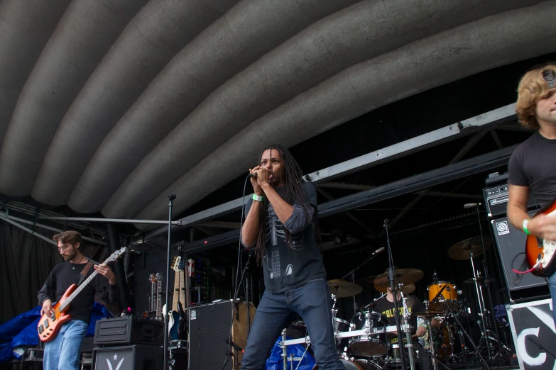 two male musicians performing on stage with another guitarist