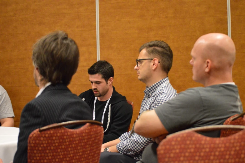 a group of men sitting on chairs talking