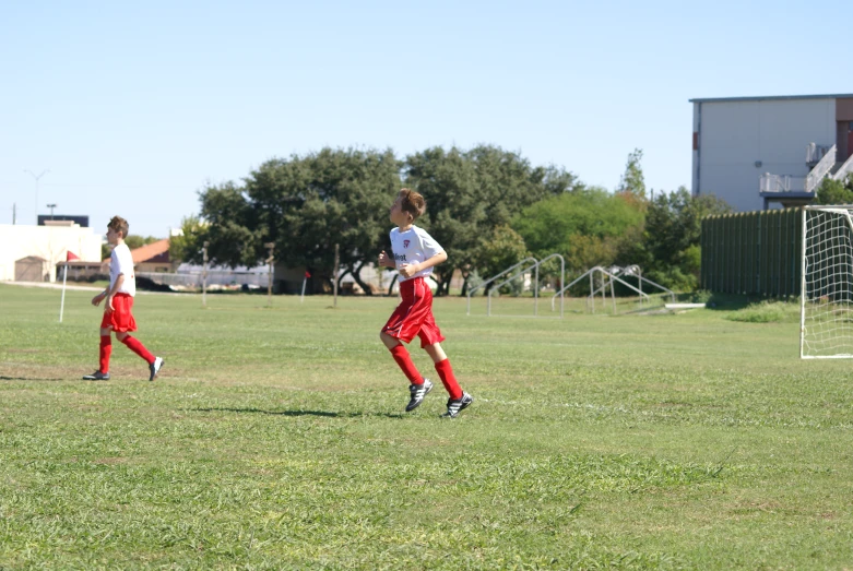 two young people playing soccer on an open field