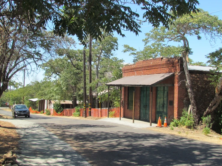 a long street with brick buildings and orange fence and trees