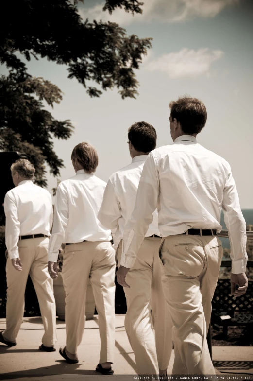 five men are walking down a sidewalk together